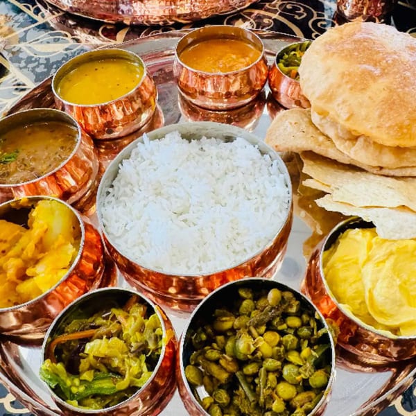 A MaanKi Thali with various Indian dishes, including rice, curries, vegetables, and bread.