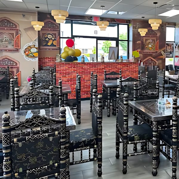 Interior of MaanKi Thali & Indian Street Food, featuring ornate black chairs and tables, and Indian-inspired wall decor.